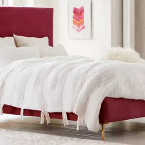 A bedroom with a burgundy upholstered bed. White Bedding.