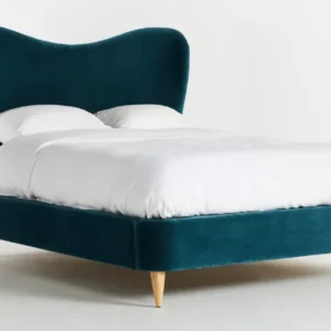 A bed with a blue velvet headboard and white bedding.