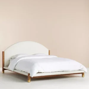 A bed with a wooden frame and a white upholstered headboard.