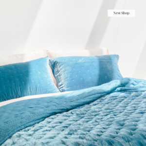 A bed with a blue silk comforter and pillows.