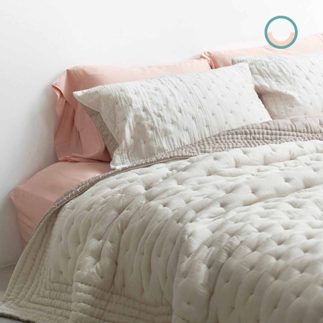 A bed with a white comforter and pink pillows.