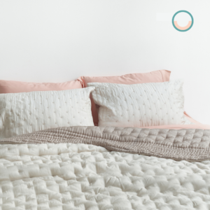 A bed with a white silk comforter and pink pillows.