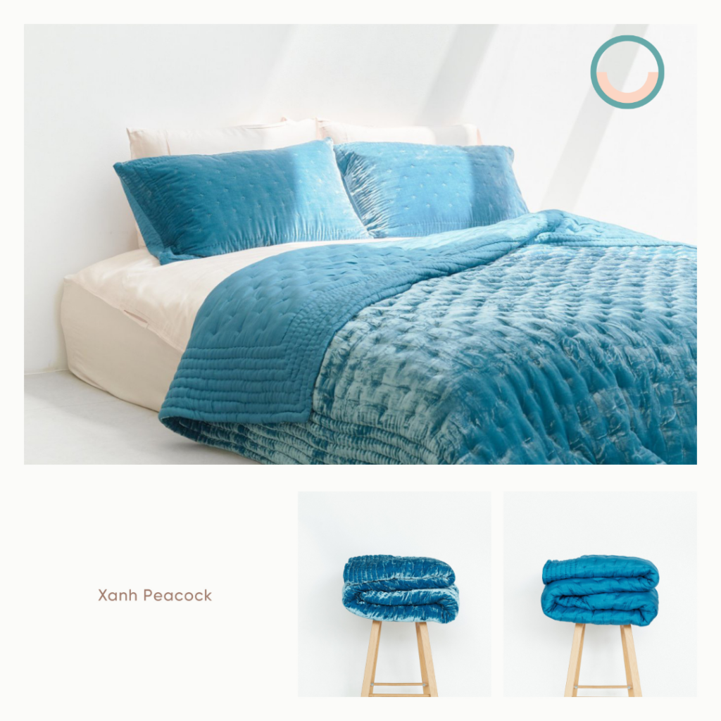 A bed with a blue silk velvet comforter and pillows.