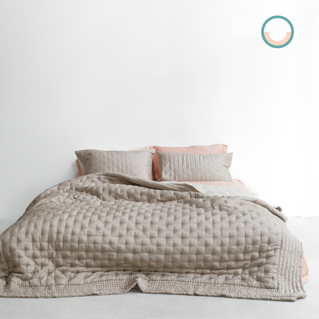 A bed with a beige silk comforter and pink pillows.