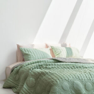A green blanket on a bed.