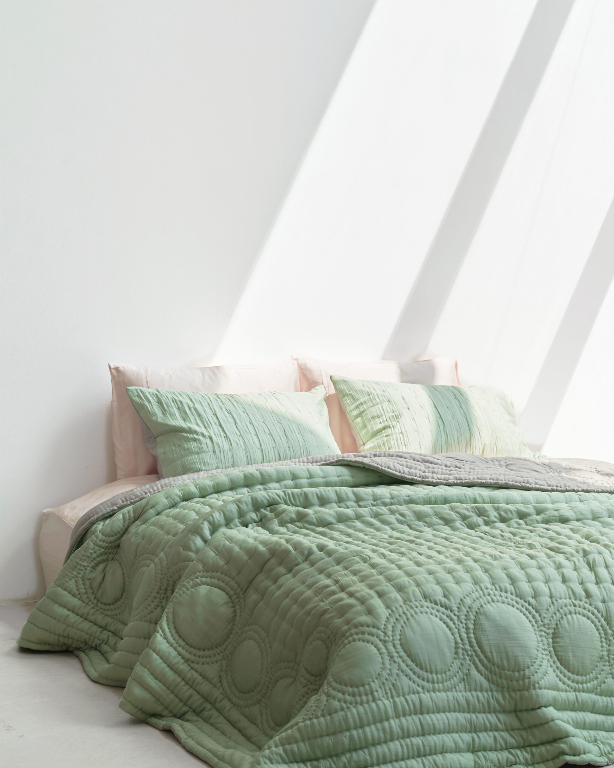 A green blanket on a bed.