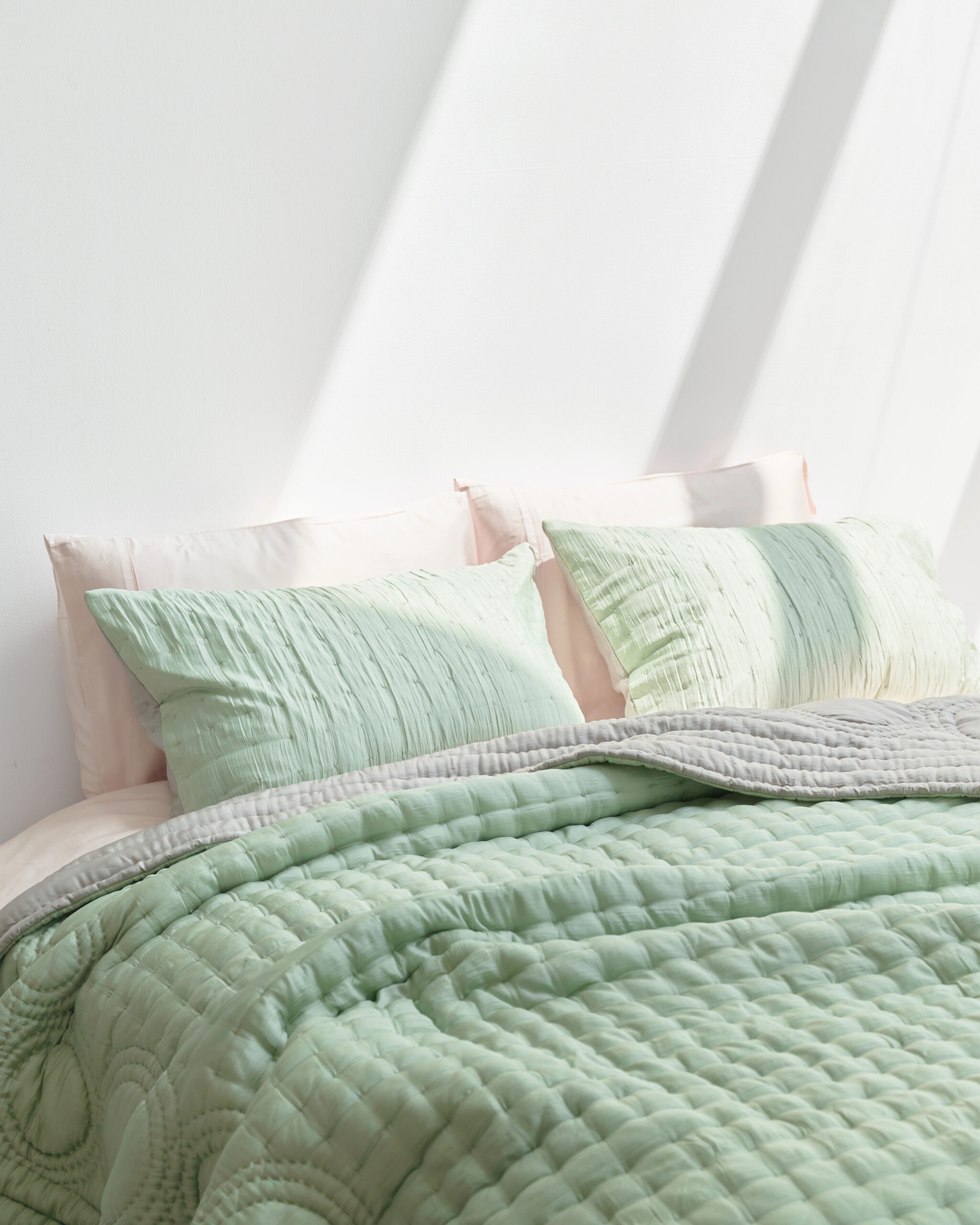 Green silk bedding on a bed.