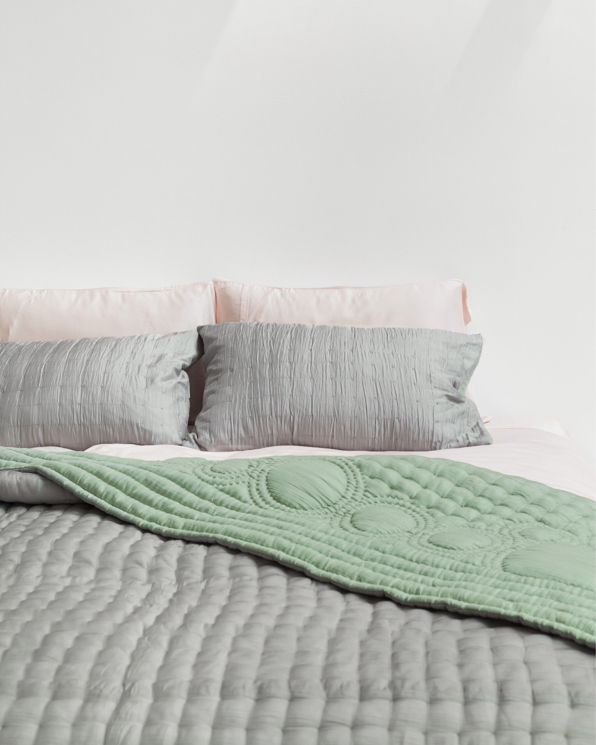 A bed with silver bedding.