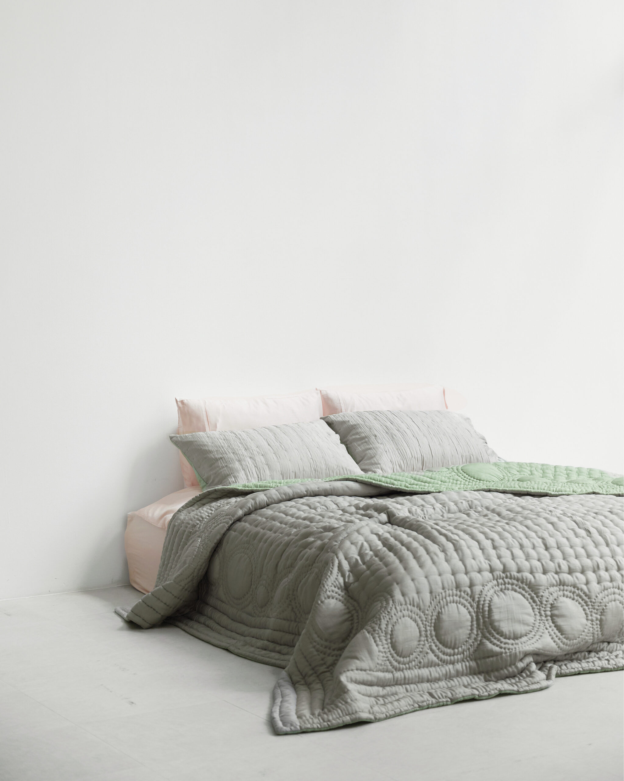 A bed with silver bedding.