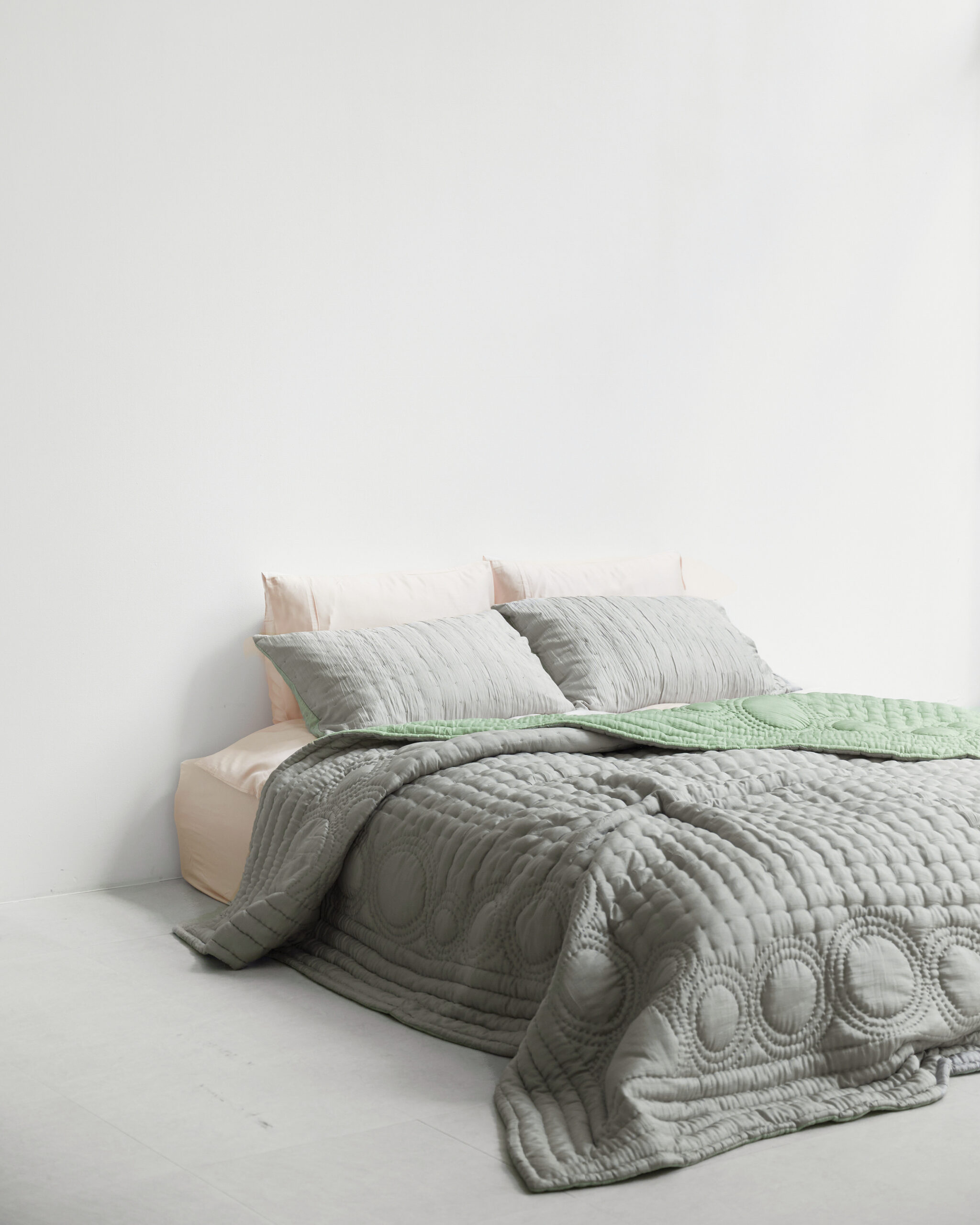 A bed with silver bedding.