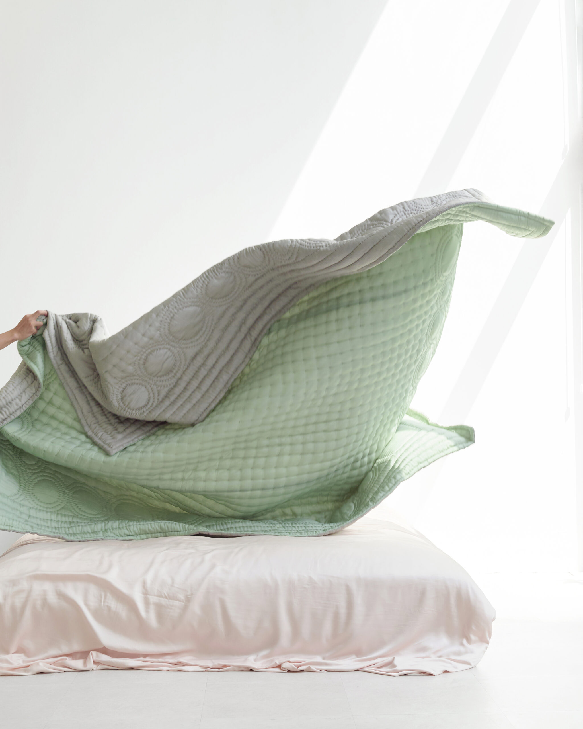 A bed with silver and green bedding.