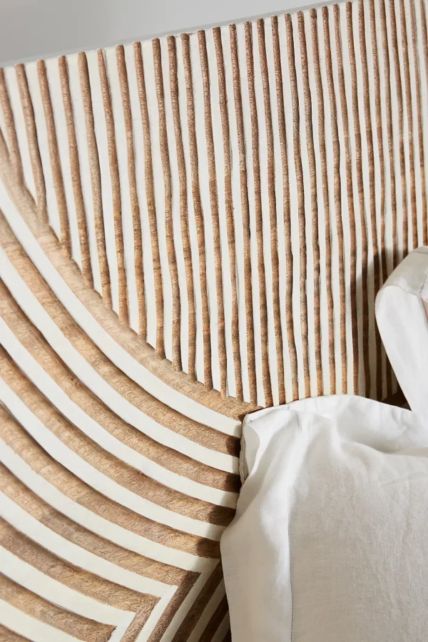 A wooden white hand carved headboard.