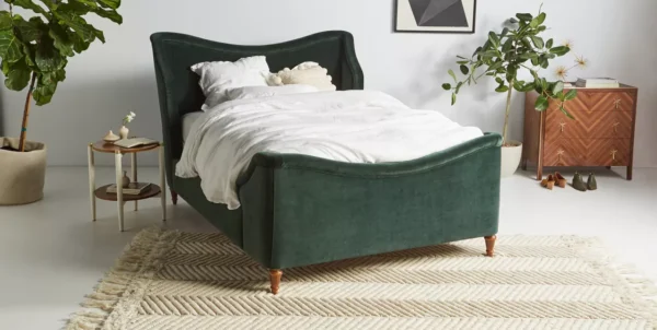 A green velvet bed in a bedroom with white bedding.