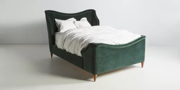 A green velvet bed in a bedroom with white bedding.