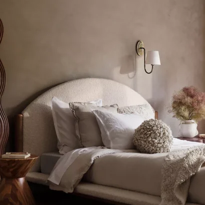 A bedroom with beige walls and a wooden bed.