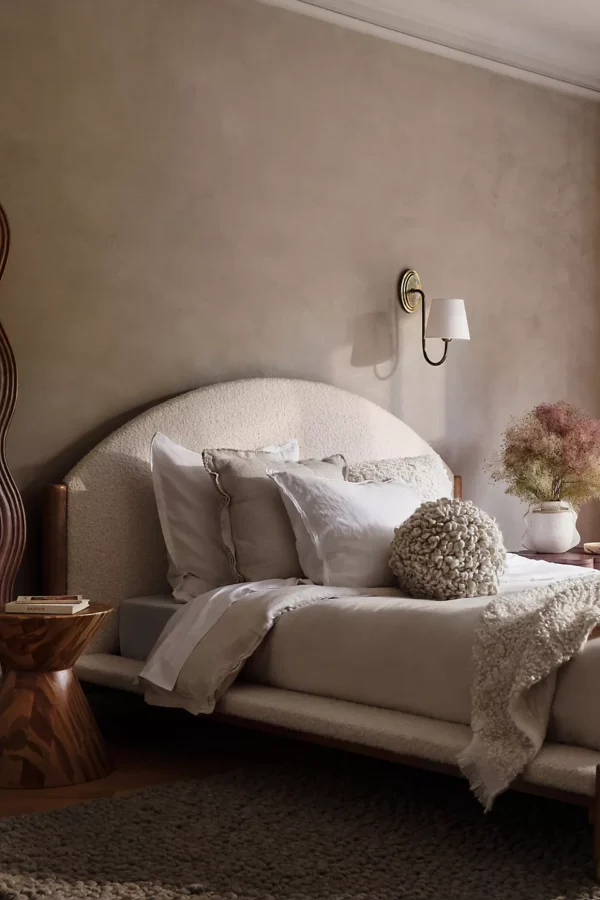 A bedroom with beige walls and a wooden bed.