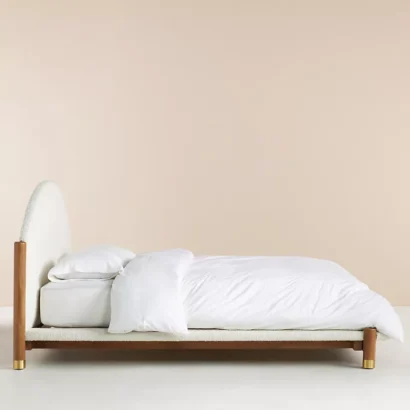 A bed with a wooden frame and a white upholstered headboard.