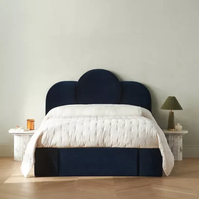 A bed in a bedroom with a blue velvet headboard.