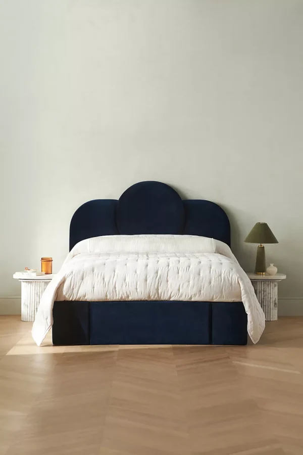 A bed in a bedroom with a blue velvet headboard.