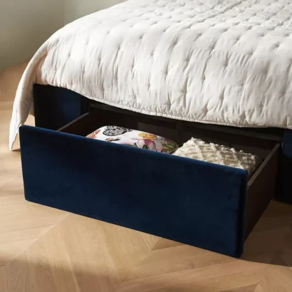 A bed with a blue velvet headboard and white bedding.