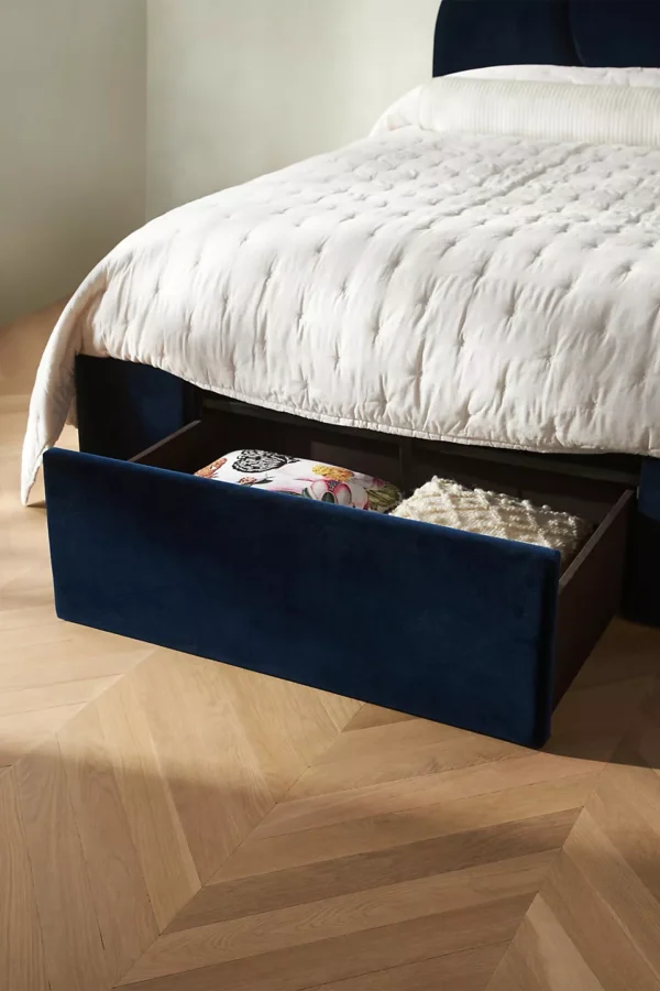 A bed with a blue velvet headboard and white bedding.