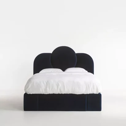 A bed with a blue velvet headboard and white bedding.