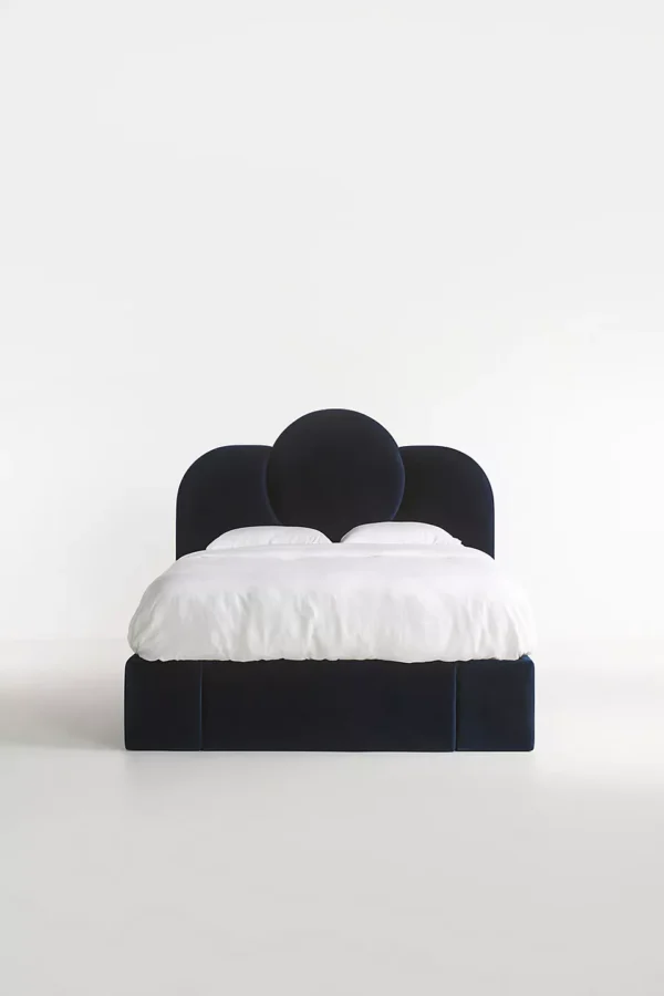 A bed with a blue velvet headboard and white bedding.