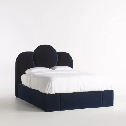 A bed with a blue velvet headboard and white bedding.