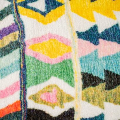 A multi-colored, eclectic patterned rug. A rug with bright colors, and diamond pattern.