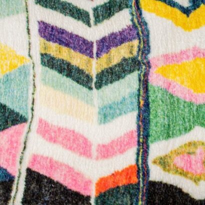 A multi-colored, eclectic patterned rug. A rug with bright colors, and diamond pattern.