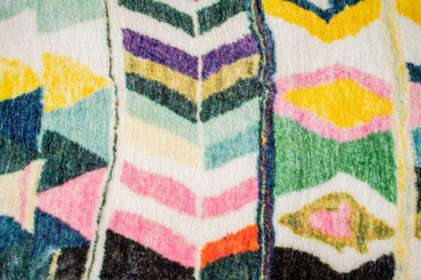 A multi-colored, eclectic patterned rug. A rug with bright colors, and diamond pattern.