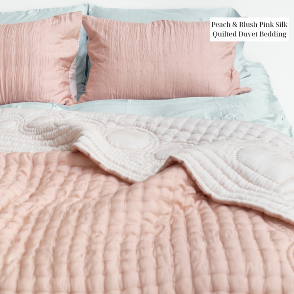 A bed with a pink quilt and pillows.